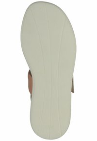 Světlé béžové sandálové podrážky, vyrobené z gumy, mají texturovaný povrch s drážkami pro lepší přilnavost. Upozorňující logo je vytlačené blízko paty.