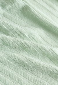 Tissu vert clair à texture fine côtelée, présentant des rayures alternées subtiles, doux au toucher et d'apparence légère.