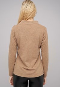 Bruine lange mouwen top met een kraag en een gestructureerde breifinish, met een ontspannen pasvorm en een lichte tapering aan de zoom.