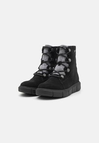 Bottines noires en daim avec une doublure en feutre gris, présentant un design à lacets et des œillets ronds noirs, montées sur une semelle épaisse noire.