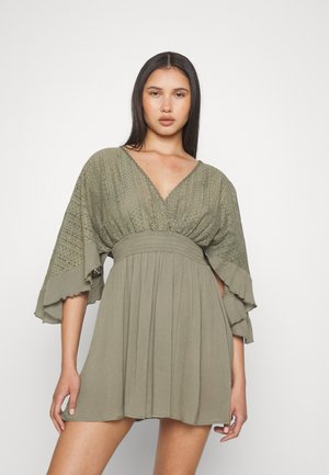 Khaki green dress featuring a V-neck, textured bodice with patterned embroidery, and flared, ruffled sleeves; flowing skirt to mid-thigh.