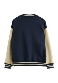 Marineblauwe en crèmekleurige bomberjack met een geribbelde kraag, contrasterende mouwen en gestreepte manchetten. Gemaakt van zacht materiaal met een gladde textuur.