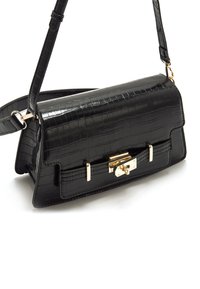 Bolso de mano negro de cuero sintético con textura de cocodrilo, forma rectangular, herrajes dorados y cierre frontal. Incluye una correa ajustable para el hombro.