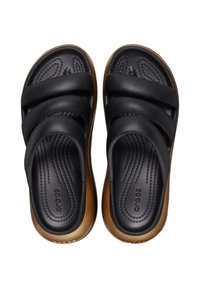 Zwarte en bruine slip-on Crocs sandalen met twee brede banden en textuur voetbedden, van bovenaf weergegeven op een witte achtergrond.