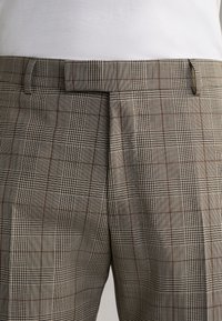 Beige karierte Hose aus strukturiertem Stoff, mit dunkelbraunen und schwarzen Karomustern, flachem Bund und Gürtelschlaufen an der Taille.