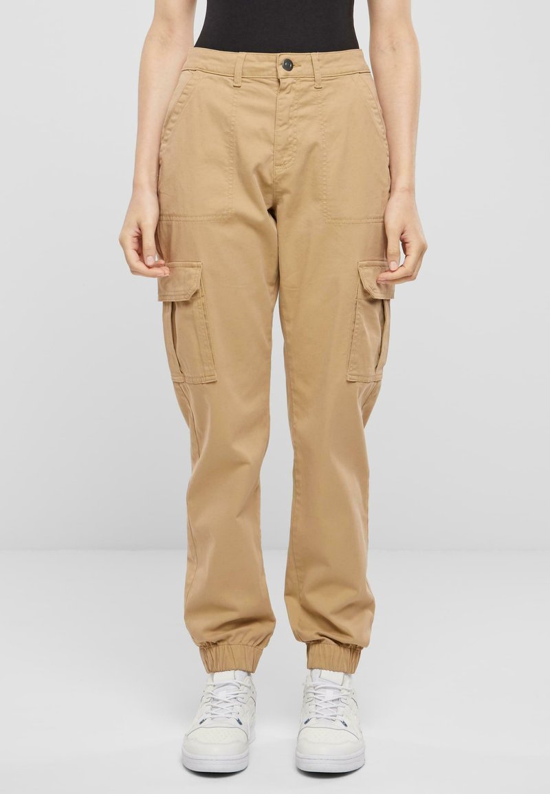 Beige cargo kalhoty s elastickými manžetami, dvěma bočními kapsami a zapínáním na knoflík. Vyrobeny z odolné bavlněné tkaniny.