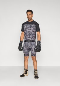Camisola atlética camuflada em preto e cinza, calções combinando, luvas de boxe pretas e botas de treino bege. Design texturizado e ajustado para desporto.