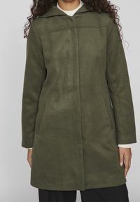Olivgrön kappa i mjukt tyg, med huva, långa ärmar och sidofickor. Rakt snitt med en ren, minimalistisk design.
