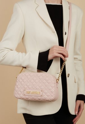 Borsa a tracolla rosa trapuntata con hardware dorato, logo impresso e una tracolla a catena. Presenta una forma rettangolare e una texture in pelle morbida.