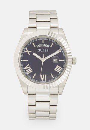 Silver metal wristwatch with a dark blue dial, Roman numerals, and a date window. Features a polished bezel and a stainless steel link bracelet.