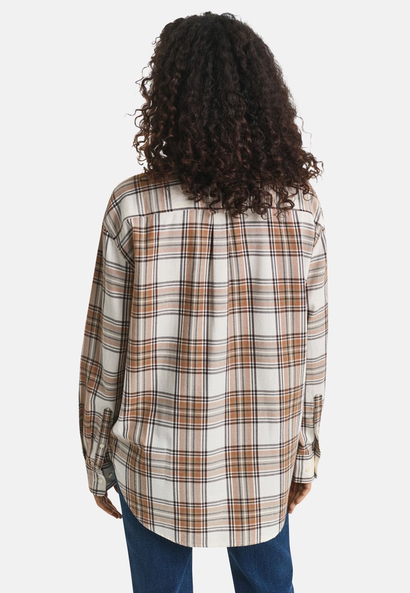 Een geruit shirt met een losse pasvorm, met bruine, beige en witte vierkanten. Gemaakt van zachte stof met een afgeronde zoom en knoopmanchetten.