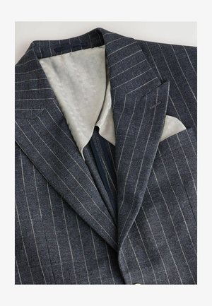 Blazer în dantelă albastru marin cu dungi, cu un căptușeală texturată de culoare gri deschis, cu rever tăiat și un buzunar pe piept care afișează o batistă albă.