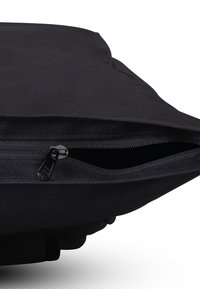Primo piano di una borsa in tessuto nero con una cerniera parzialmente aperta che mostra l'interno vuoto su sfondo bianco.