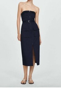 Robe bleu marine sans bretelles avec une fermeture éclair à l'avant, deux poches frontales, une taille ceinturée et une fente au genou. Tissu lisse, design minimaliste.