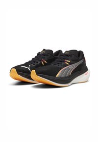 Čierne športové topánky s textilným vrchom, s výrazným logom Puma, oranžovými akcentmi a textúrovanou gumovou podrážkou pre lepšiu priľnavosť.