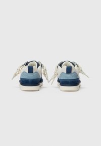 Blå och marinblå sneakers med en strukturerad överdel i mocka och nät, med en gräddfärgad tunga och kontrasterande snören.