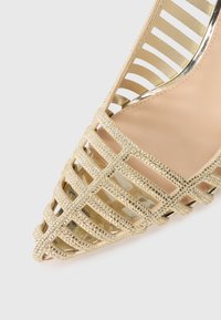 Scarpe open-toe dorate con un motivo incrociato, adornate con piccoli strass, caratterizzate da una suola interna liscia e dettagli metallici.
