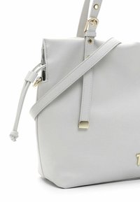 Sac à épaule en cuir gris clair avec bandoulière réglable, détail côté à cordon et accessoires dorés.