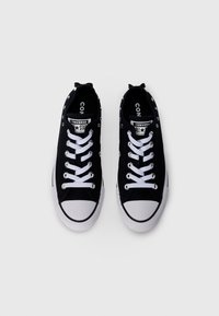 Must musta mustad Converse'i kõndimiseks sobivad madalad mustad kingad valgete paelte ja varvastega, vaadatuna ülevalt valge tausta peal.