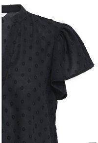 Blouse noire semi-transparente avec pois texturés, manches courtes bouffantes et col rond.