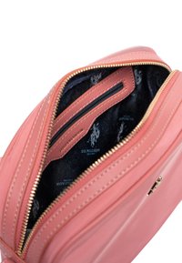 Borsa in pelle rosa con cerniera dorata, che mostra un interno in tessuto scuro con motivo a logo. Include scomparti per carte e ha una texture liscia.