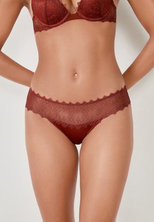Intimo in pizzo rosso con vita ondulata e motivo floreale, caratterizzato da una miscela di tessuti lisci per un aspetto e una sensazione eleganti.