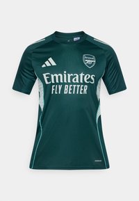 Grøn fodboldtrøje med korte ærmer, der har hvide detaljer og "Emirates Fly Better" logo. Adidas-logo på skulderen, AeroReady mærkat synlig.