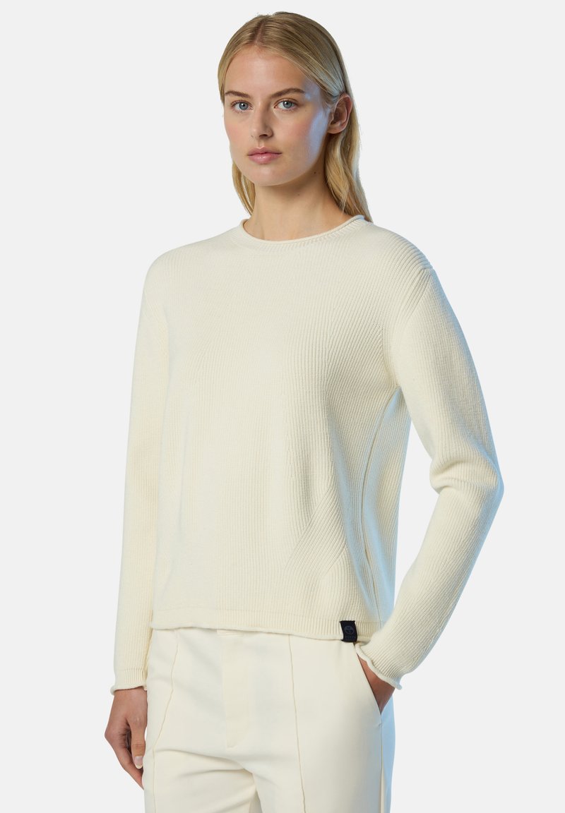 Maglione a coste di colore crema chiaro con maniche lunghe e scollo tondo, dotato di una piccola etichetta nera sull'orlo. Texture morbida.