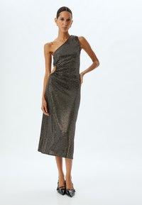 Ein schwarzes und metallisches Kleid mit einem Schulterträger, das eine figurbetonte Silhouette aufweist, seitliche Ausschnitte hat, knielang ist und dezenten Glanz durch Pailletten bietet.
