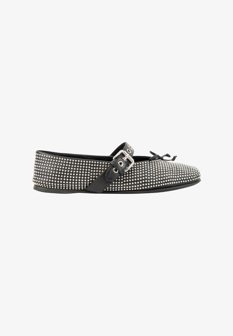 Chaussure plate noire recouverte de petits clous argentés avec une bride noire à boucle et un nœud décoratif à l'avant.