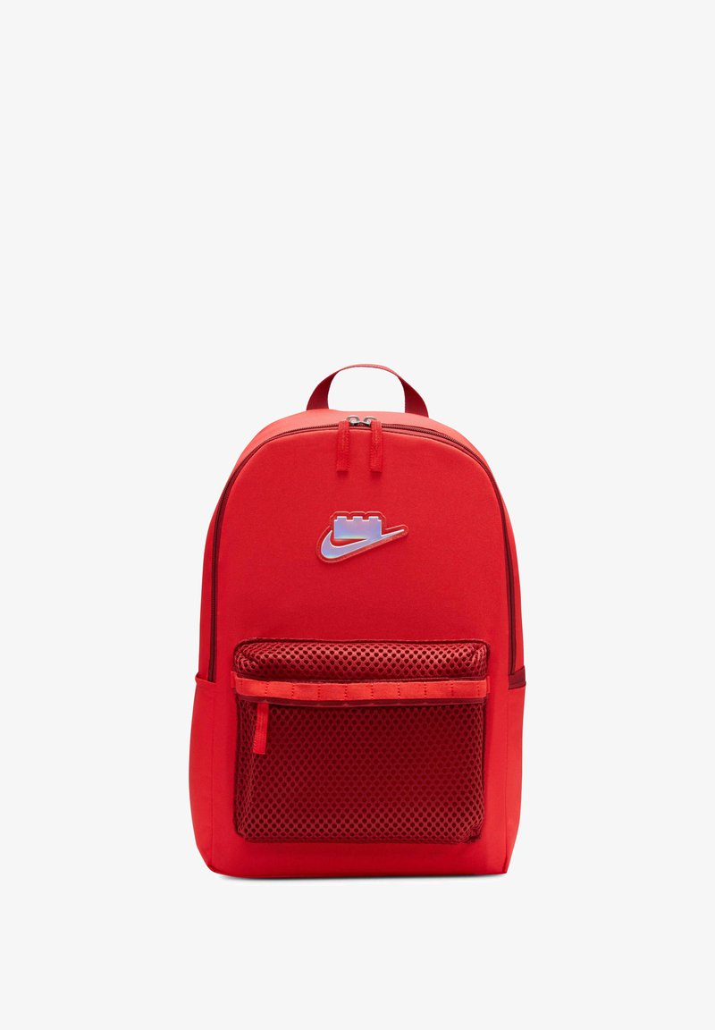 Zaino rosso realizzato in tessuto resistente, dotato di un vano principale con zip, una tasca frontale in rete e un logo ben visibile nella parte superiore.