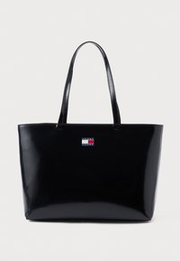 Fekete fényes vászontáska két fogóval. Téglalap alakú, az elején kis logóval, amely piros, fehér és kék színekben pompázik.