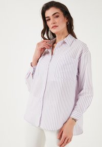 Button-up shirt in lightweight fabric, featuring vertical purple stripes on a white background, with a chest pocket and long sleeves.