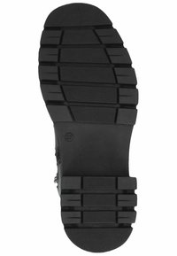 Black rubber sole of a shoe featuring a multi-grooved tread pattern for traction, with raised sections and textured details for grip.