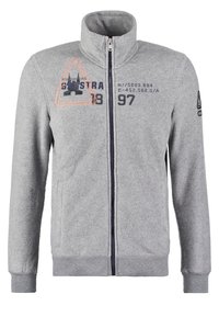 Giacca in pile grigia con collo alto, chiusura con zip, tasche laterali e stampe blu navy e arancioni sul davanti. Polsini a costine.