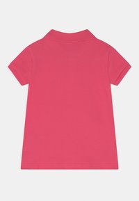 Różowa koszulka polo z prążkowanym kołnierzem i krótkimi rękawami, o gładkiej fakturze i prostym kroju, pokazana od tyłu.