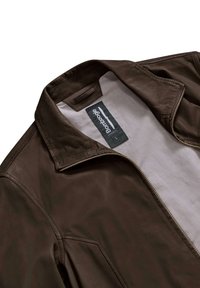 Giubbotto in pelle marrone con zip frontale, colletto a punta e etichetta interna. Presenta una texture liscia e un design strutturato.