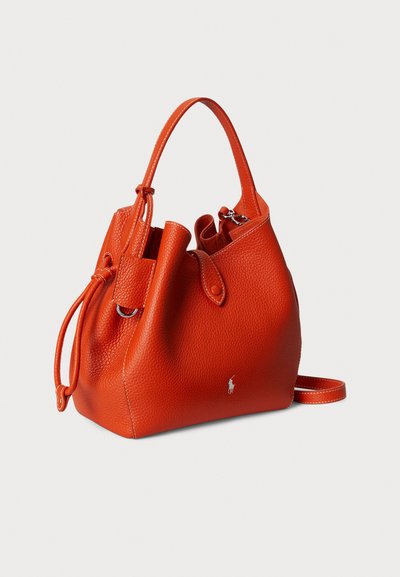 Oranžna usnjena torbica v obliki vedra z teksturirano površino, zavezovanjem s vrvico in kratkim ročajem. Na sprednji strani ima majhen logotip.