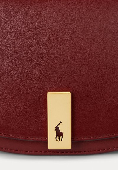 Bolsa de couro vermelha com uma textura suave, ferragens douradas e um acento de logótipo em destaque. O design é elegante, com uma forma retangular plana.