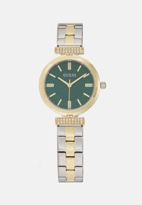 Orologio in metallo dorato e argentato con quadrante verde, caratterizzato da un motivo testurizzato, dettagli in cristallo e cassa rotonda. Cinturino in stile bracciale con maglie.
