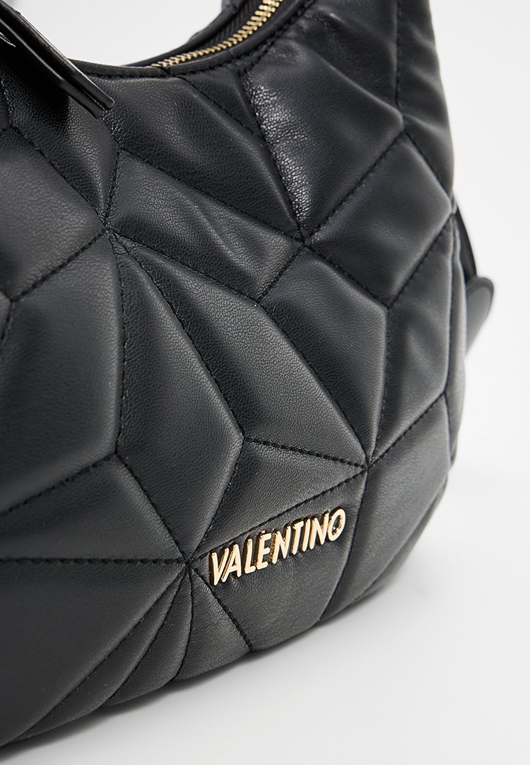 Bolso de mano de cuero negro con patrón geométrico acolchado y herrajes dorados. Presenta un cierre de cremallera y logotipo de la marca en relieve en la parte frontal.