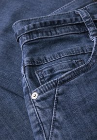 Džínové kalhoty tmavě modré barvy, s přední kapsou, kontrastním šitím a kovovým nýtem. Hladká textura, le žérní design.