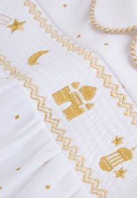 Tissu blanc avec motifs de mosquée brodés en or, étoiles, croissants de lune et bordures en zigzag, accompagné d'un cordon torsadé or et blanc.