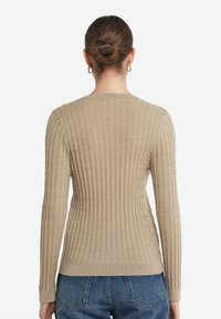 Beżowy sweter wykonany na drutach z teksturowanym prążkowanym wzorem. Długie rękawy i dopasowany krój, z okrągłym dekoltem i prążkowanym wykończeniem.