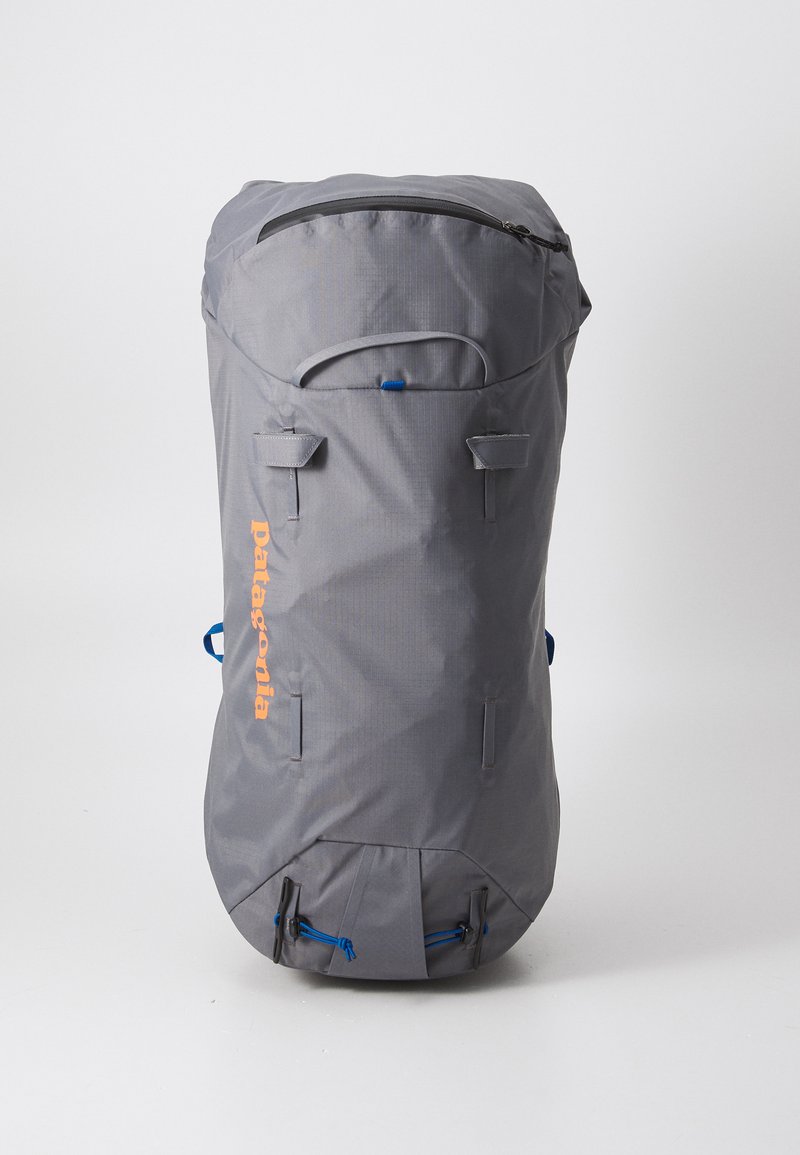 Gray backpack with a cylindrical shape, made of fabric. Features a top zipper, blue accents, and an orange logo. Includes adjustable straps.
