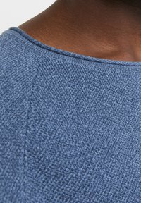 Pulover bleu din tricot cu un model texturat, guler rotund și detalii de cusătură vizibile. Fabrică din amestec de bumbac cu un aspect moale.