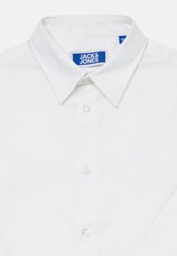 Biała koszula z guzikami z ostrym kołnierzykiem oraz metką "Jack & Jones" wewnątrz kołnierzyka.