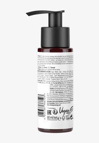 Shampooing nettoyant en profondeur dans une bouteille ambre foncé avec une pompe noire, affichant un texte et des logos sur l'étiquette arrière. Taille : 80 ml. Certifié végan et EAC.