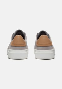 Sneakers med en grå mockaöverdel och beige läderdetaljer, med en vit gummisula och strukturerad tyginredning. Bakifrån visad.