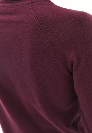 Bordeaux trui met fijne brei textuur, hoge kraag en opvallende naaddetails langs de schouder en zijpaneel.